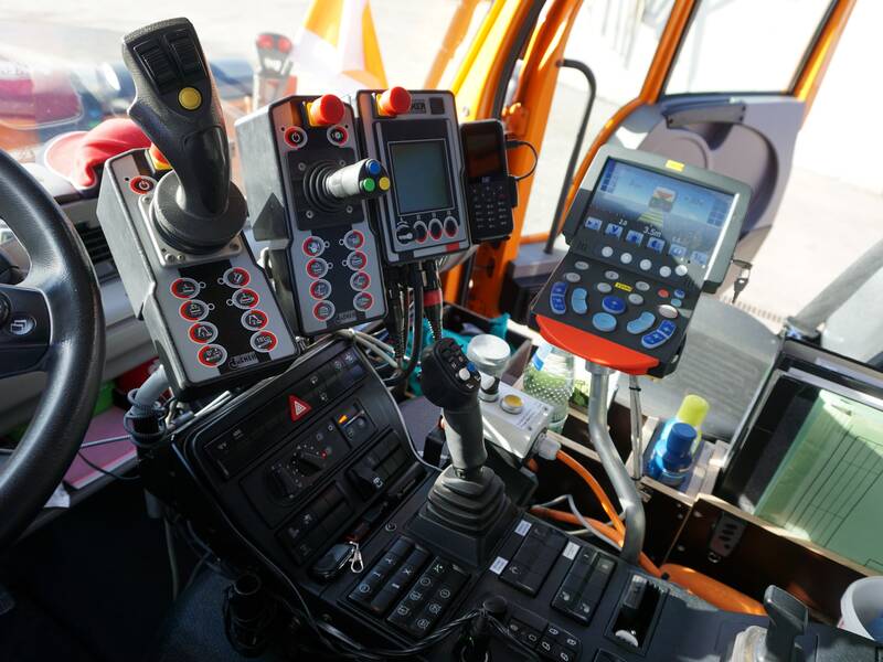 Das Bild zeigt das Cockpit eines Spezialfahrzeugs mit zahlreichen Hebeln, Steuerungen und Monitoren.