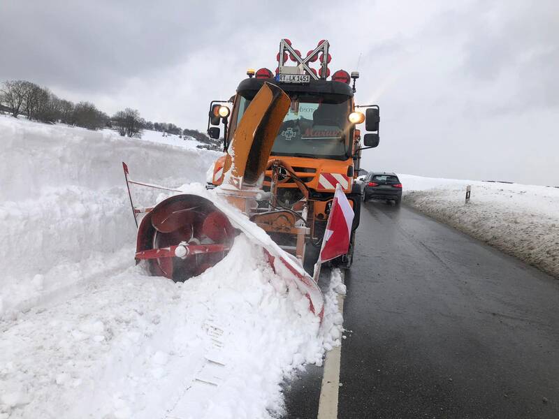 Ein Winterfahrzeug schleudert den Schnee auf einer Straße zur Seite.