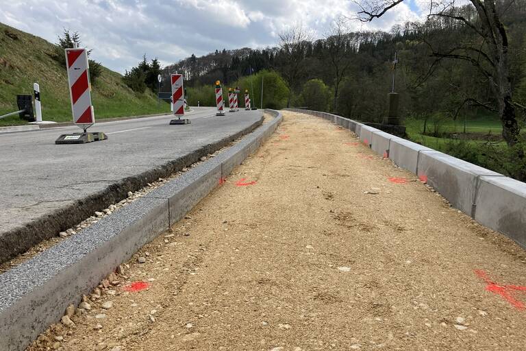 Links verläuft eine Straße, rechts daneben ist ein erdiger Weg, der gearde umgebaut wird.