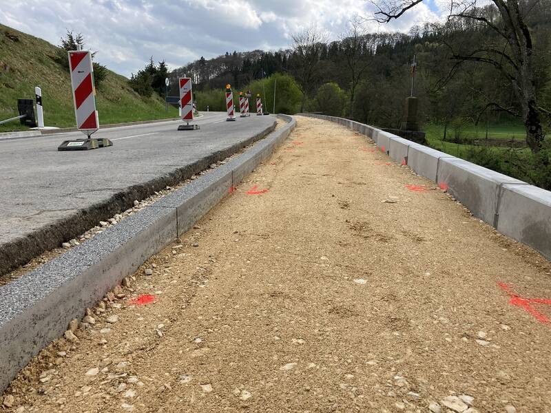 Links verläuft eine Straße, rechts daneben ist ein erdiger Weg, der gearde umgebaut wird.