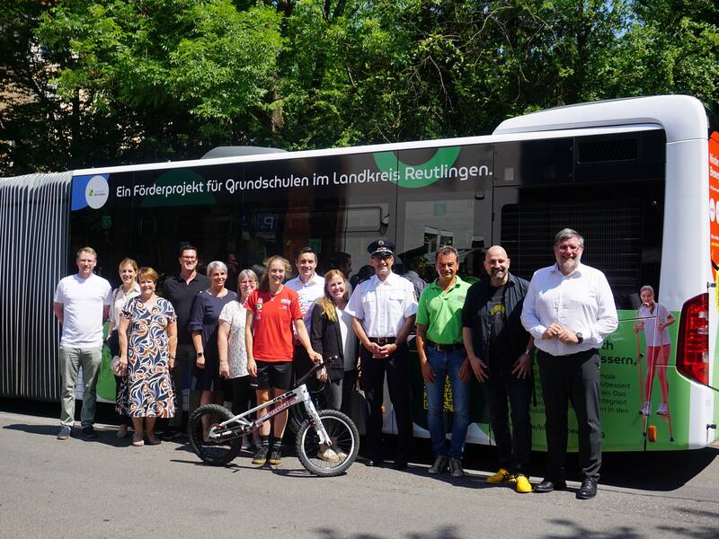 Gruppenbild mit 13 Personen der Kooperationspartner des Projekts Kinder in Bewegung stehen vor dem beklebten Linienbus der RSV.