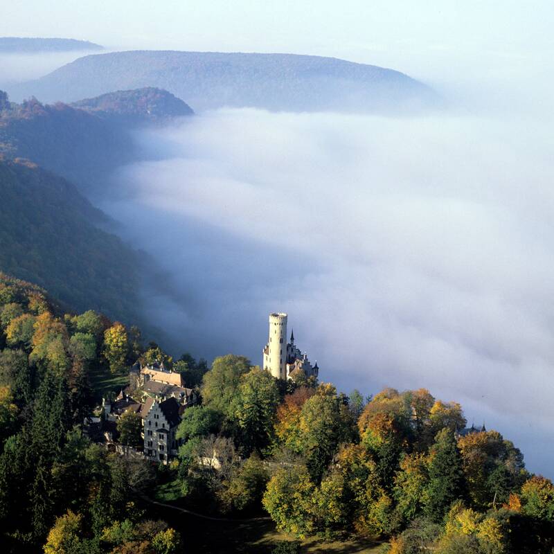 Luftbild auf das Schloss Lichtenstein, seitlich Nebel und Wald