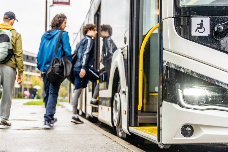 Drei ältere Teenager steigen in einen Bus ein.