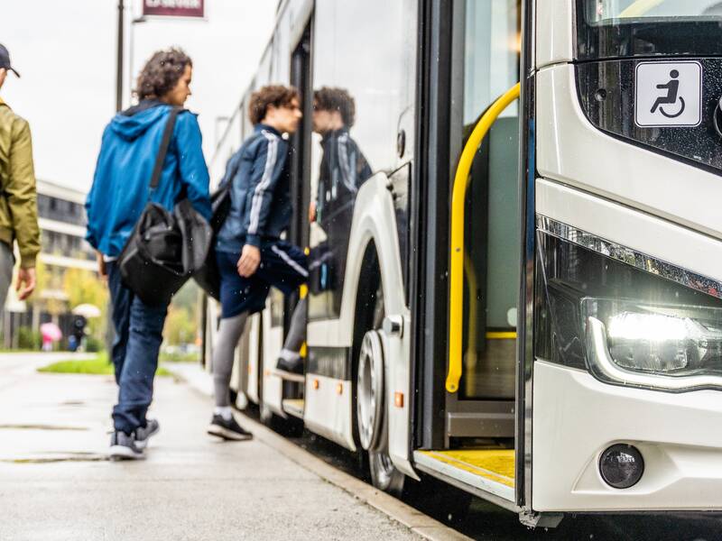 Drei ältere Teenager steigen in einen Bus ein.