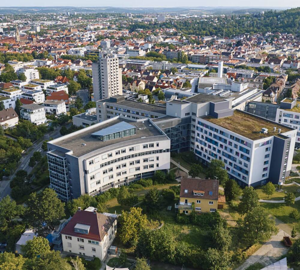 Luftaufnahme der Kreisklinik Reutlingen mit begrünten Dächern, umgeben von städtischer Bebauung und dichter Vegetation bei Tageslicht.