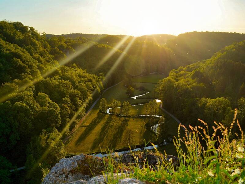 Ein Tal, das von der Sonne beschienen wird. Durch das Tal zieht sich ein Fluss.