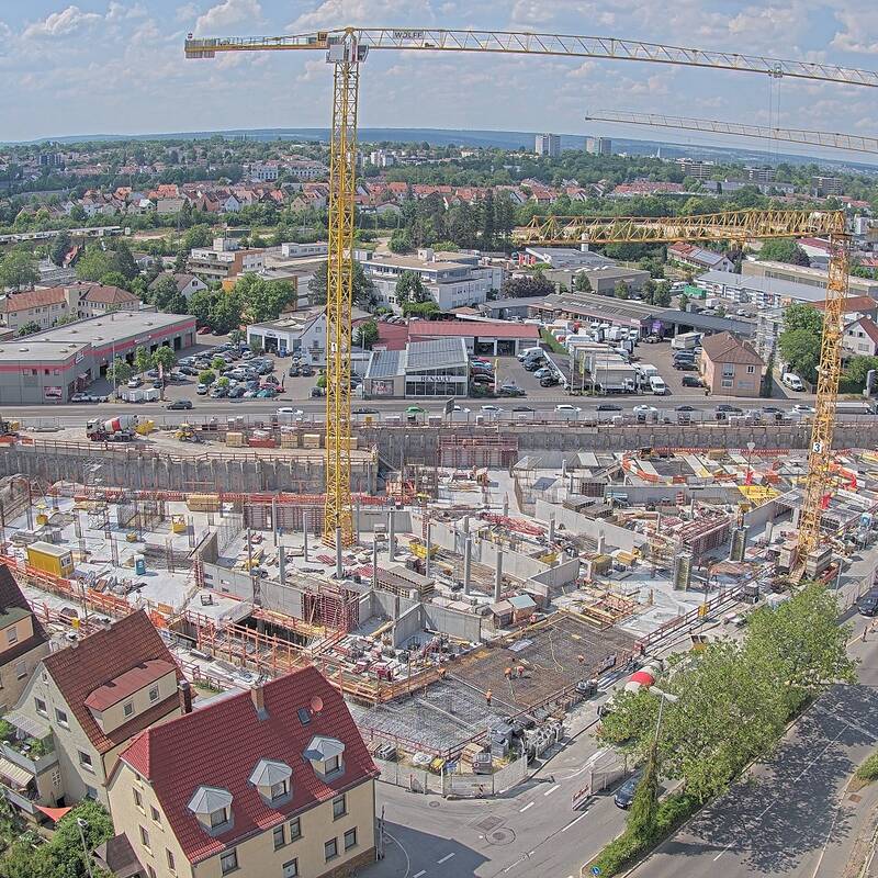 Eine Baugrube von oben. In der Grube stehen zwei gelbe Kräne.