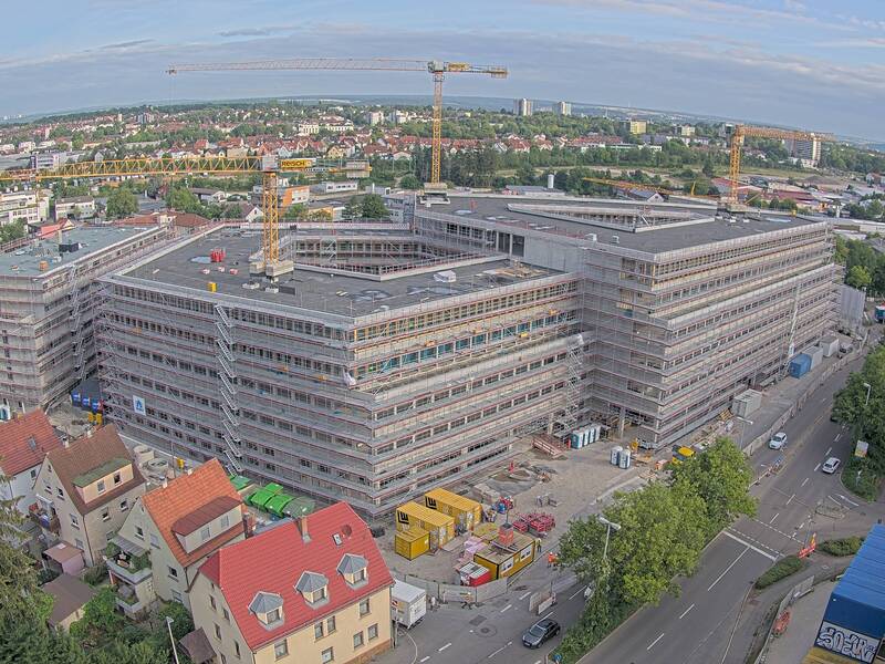 Luftbild eines fünfstöckigen Neubaus, der sich noch im Bau befindet. Das Gebäude besteht aus zwei überlappenden Dreiecken.