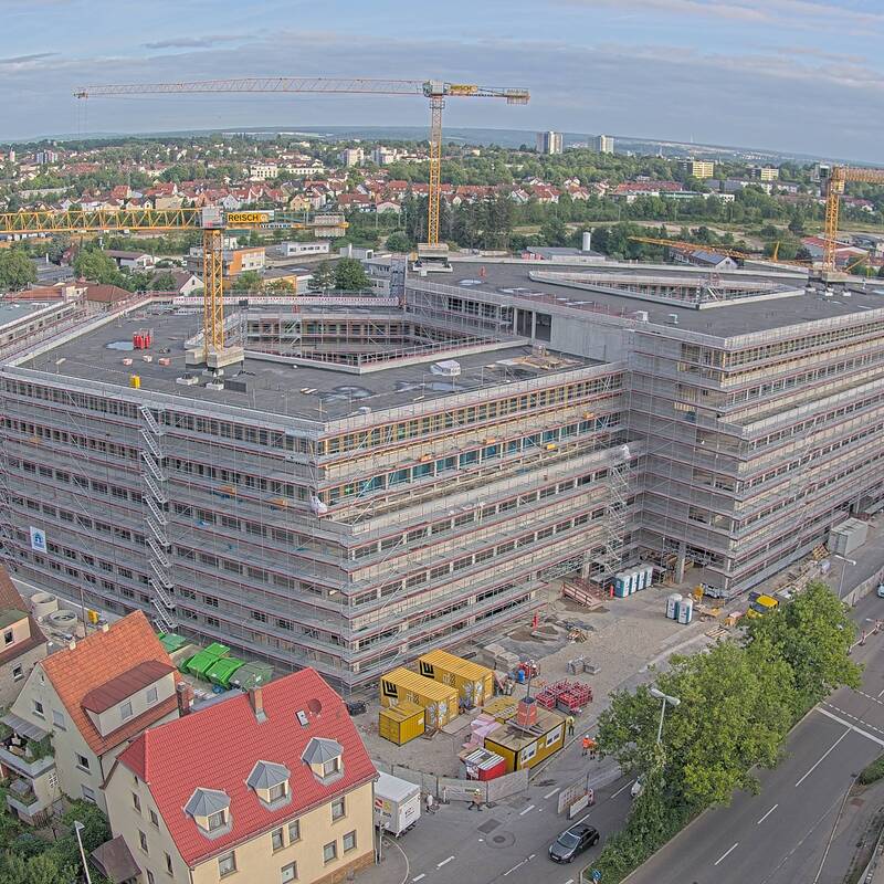 Luftbild eines fünfstöckigen Neubaus, der sich noch im Bau befindet. Das Gebäude besteht aus zwei überlappenden Dreiecken.